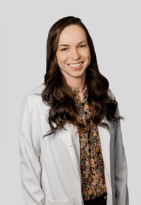 Female Provider wearing brown shirt standing infront of white background.