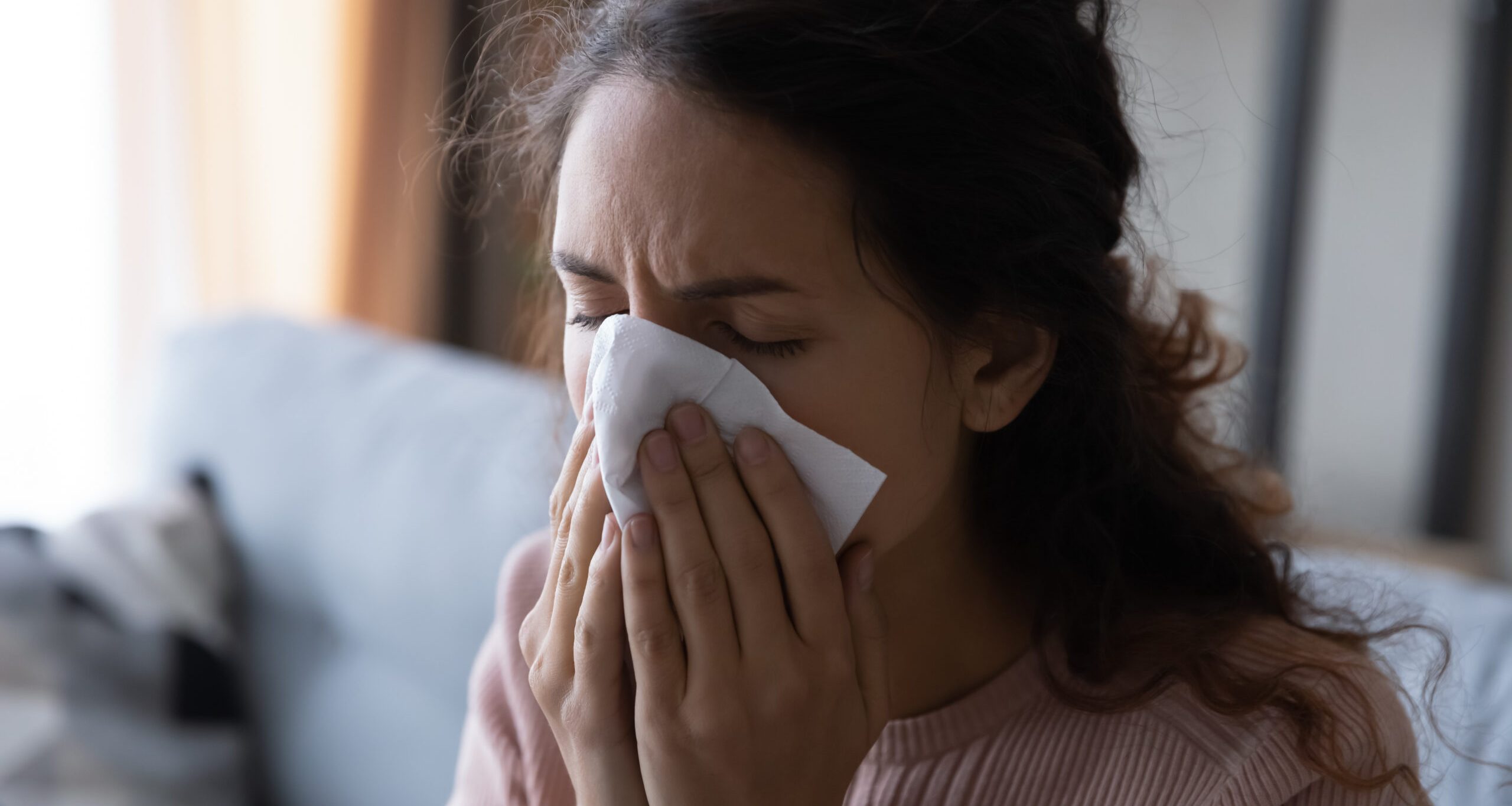 Unhealthy young lady using paper tissue, wiping runny nose.